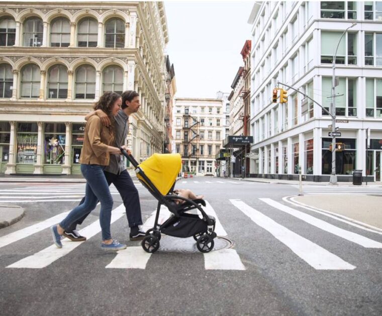 Couple pushing a baby stroller across a street in a city