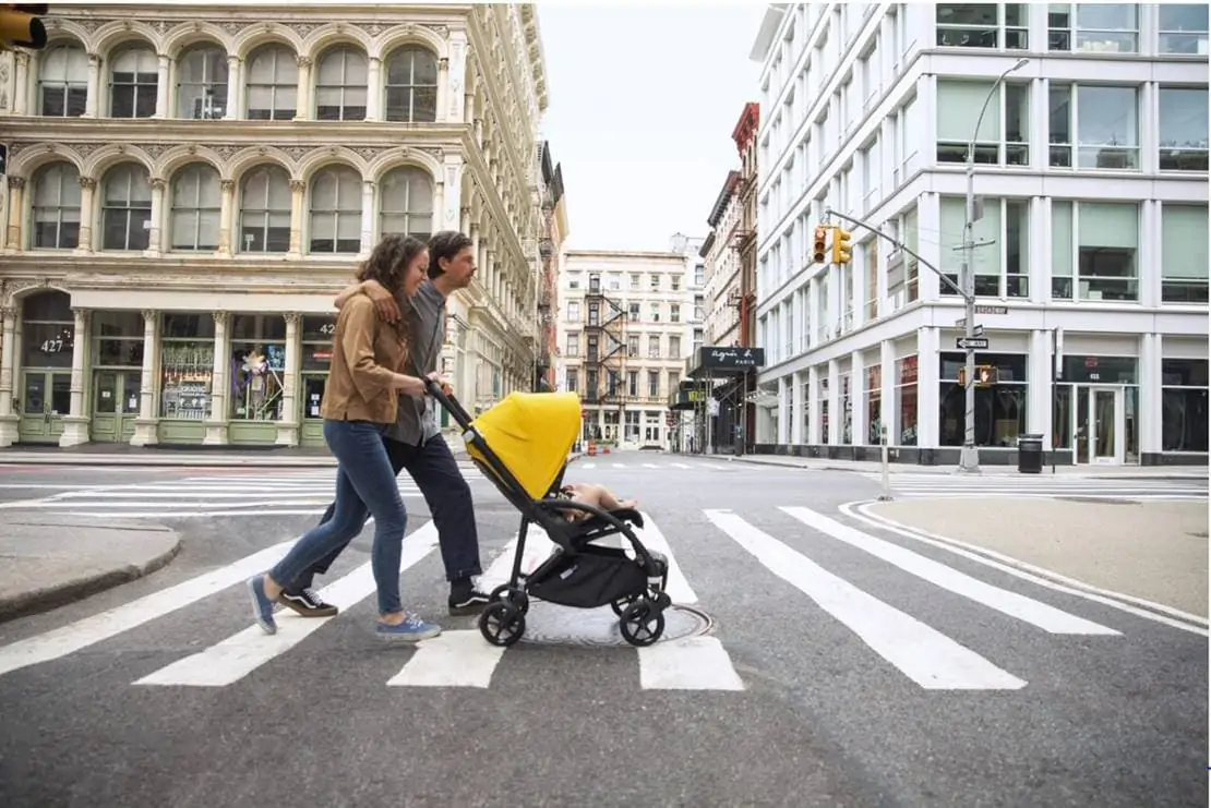 Couple pushing a baby stroller across a street in a city